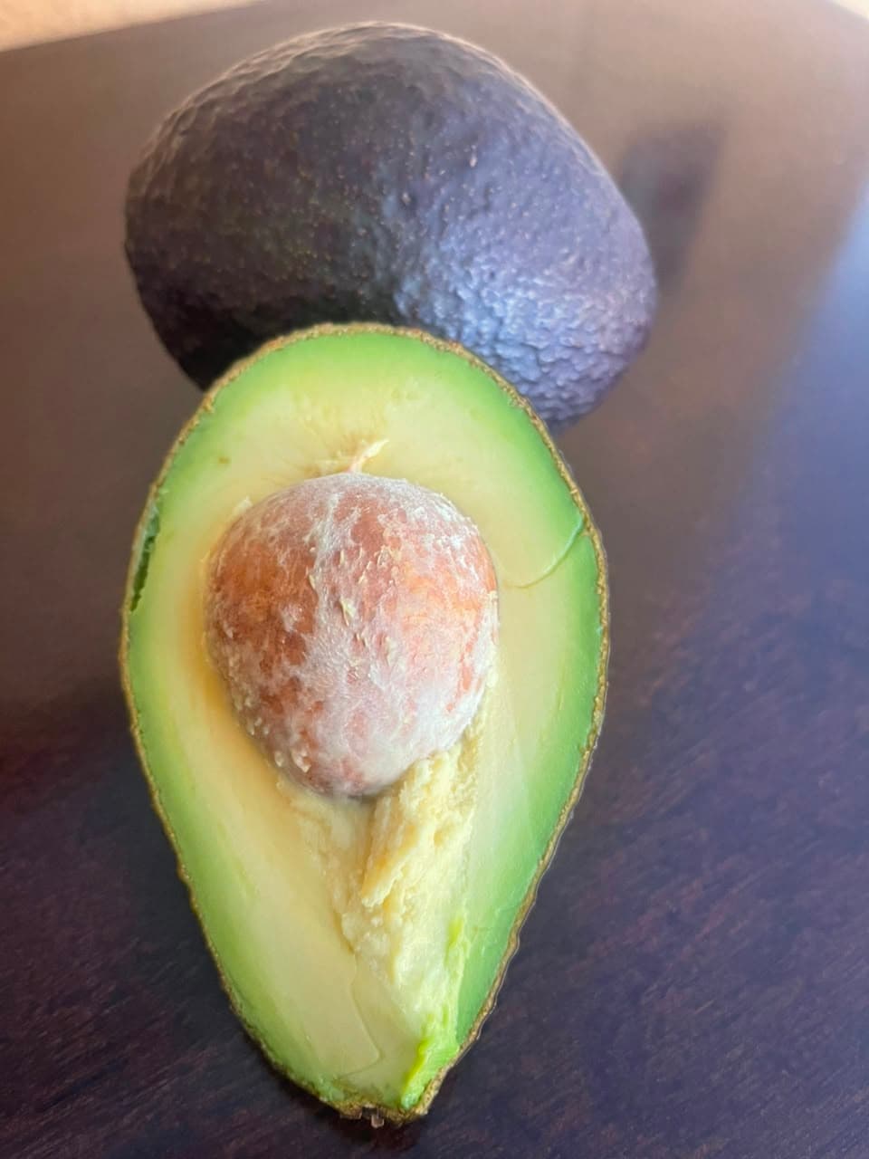 Palta Hass entera y en corte transversal mostrando pulpa y carozo